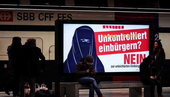 La gente camina junto a carteles electorales contra el uso de la burka. (AFP).