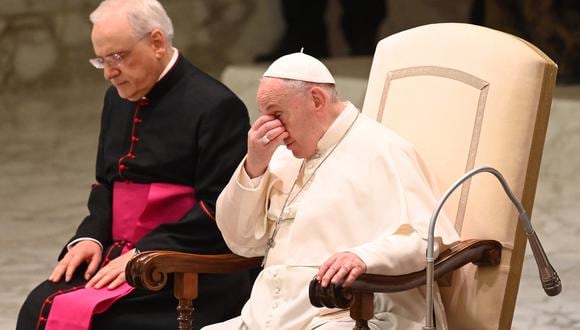 El Papa Francisco sentado junto a Mons. Leonardo Sapienza, se toca la cara cuando se encuentra con los fieles durante su audiencia general semanal en la sala Pablo VI del Vaticano. (Foto: Vincenzo PINTO / AFP)