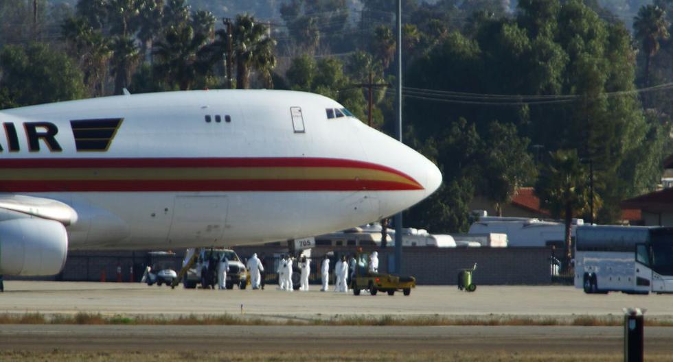 El personal con trajes de riesgo biológico aguarda a los pasajeros evacuados de Wuhan, poco después de que el avión aterrizó en la Base de la Reserva Aérea March en Riverside, California, el 29 de enero de 2020. (AFP).