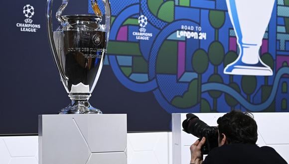 Un hombre toma una fotografía de la copa de la Liga de Campeones de la UEFA antes del sorteo de octavos de final del torneo de fútbol de la Liga de Campeones de la UEFA 2023-2024 en la Casa del Fútbol Europeo en Nyon, el 18 de diciembre de 2023. (Foto de Fabrice COFFRINI / AFP)