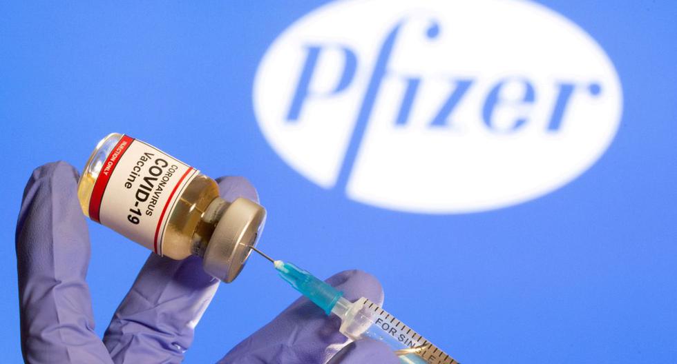 Una mujer sostiene una pequeña botella con una etiqueta de "Vacuna contra el coronavirus COVID-19" y una jeringa médica frente al logotipo de Pfizer. (REUTERS/Dado Ruvic).