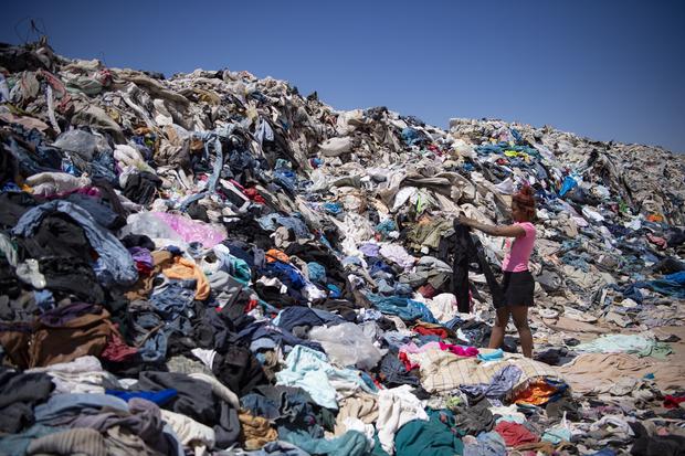 Aldo Hospice, Chile, searches for used clothing by a woman among tons of discarded clothing in the Atacama Desert in Ecuador.  (Photo: Martin Bernetti / AFP)
