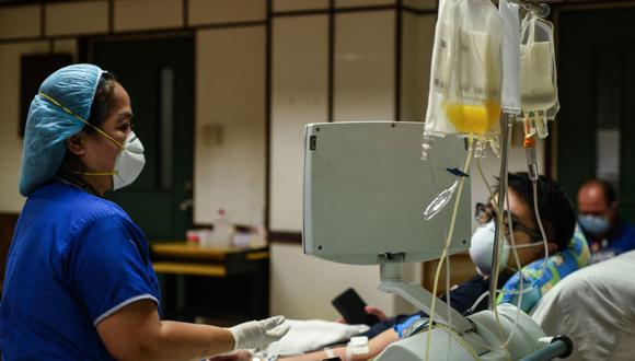 Imagen referencial. Una enfermera (izquierda) revisa a un paciente en un hospital, el 22 de abril de 2020. (Maria TAN / AFP).