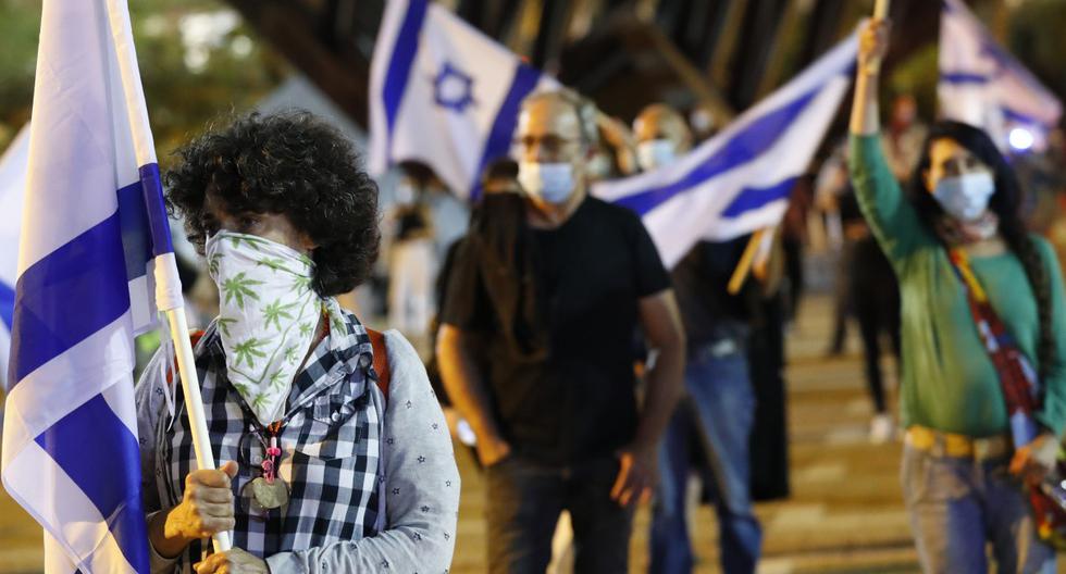 Imagen referencial del 9 de mayo de 2020. Los ciudadanos, con máscaras protectoras y de pie a dos metros de distancia debido a la pandemia del coronavirus, son vistos reunidos en la ciudad costera israelí de Tel Aviv. (JACK GUEZ / AFP).