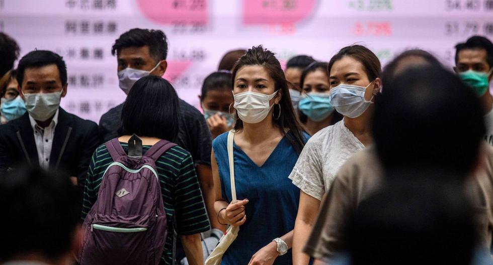 Imagen referencial. Los peatones usan mascarillas contra el coronavirus mientras cruzan una calle en Hong Kong. (AFP / Anthony WALLACE).