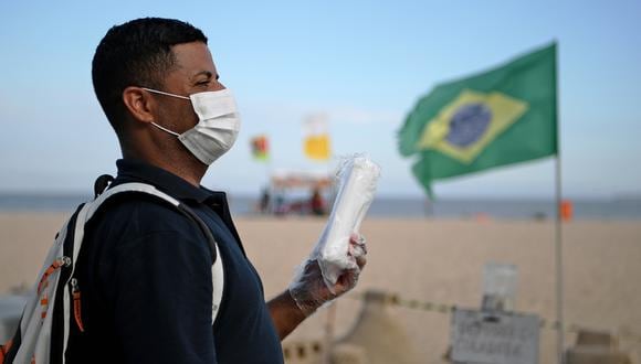 Un vendedor ambulante vende máscaras faciales como medida preventiva contra la propagación del nuevo coronavirus, COVID-19, en la playa de Copacabana en Río de Janeiro, Brasil. (Foto: AFP)