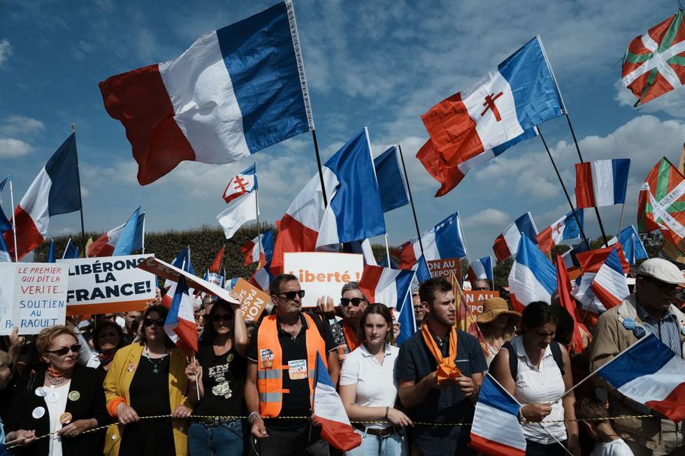Los manifestantes sostienen banderas y carteles franceses que dicen "Libertad", en el centro, y "Francia libre", a la izquierda, durante una manifestación contra el pase de salud, en París, el sábado 4 de setiembre de 2021. (AP/Thibault Camus).