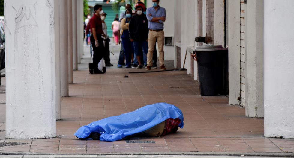 Las personas hacen cola frente a una tienda cerca del cadáver de un hombre en la ciudad de Guayaquil. Ecuador ha reportado 75 muertos por coronavirus. (REUTERS/ Vicente Gaibor del Pino).