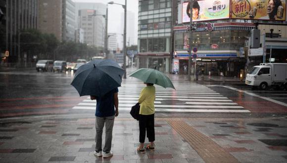 Las personas se protegen con sombrillas cuando caen las fuertes lluvias causadas por el tifón en Tokio. (Foto referencial: AFP)