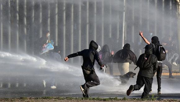 La policía antidisturbios rocía agua para dispersar a los estudiantes durante una protesta por más recursos educativos en Santiago el 9 de septiembre de 2022. (Foto de MARTIN BERNETTI / AFP)