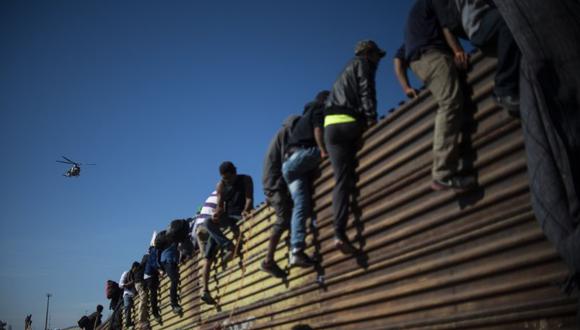 En grupos pequeños, decenas de migrantes de la caravana se desviaron de una ruta prevista, burlaron un cerco policial y trataron de trepar el muro fronterizo por varios puntos | Foto: AFP