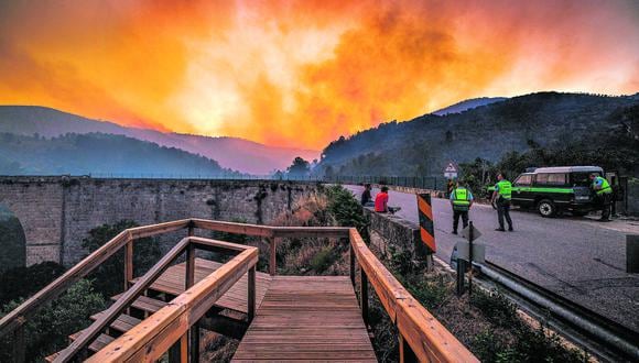 EN PORTUGAL. Transeúntes y agentes de la guardia nacional miran un incendio forestal en Valpacos (norte). Miles tuvieron que evacuar. (Foto: EFE)