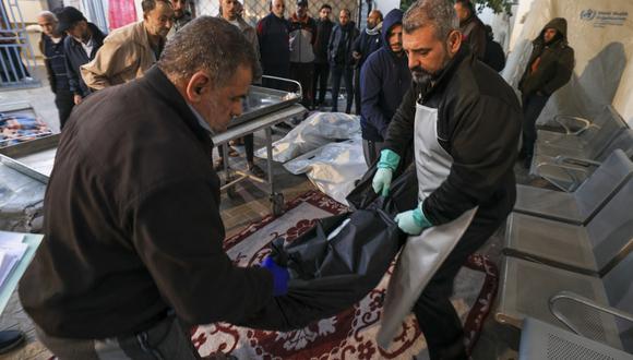 Los médicos colocan el cuerpo de una víctima muerta durante el bombardeo israelí frente al hospital al-Najjar en Rafah, en el sur de la Franja de Gaza, el 11 de diciembre de 2023. (Foto: Mahmud HAMS / AFP)