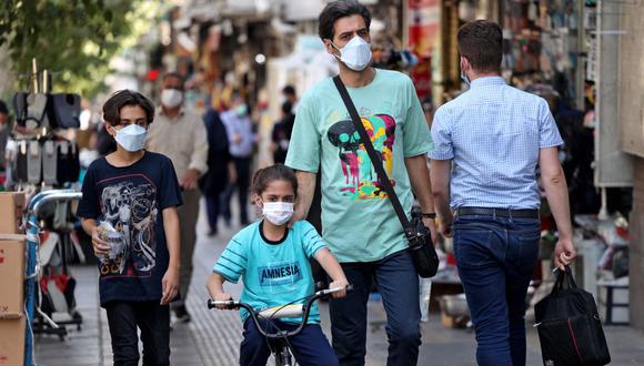 Los iraníes llevan mascarillas como medida contra el coronavirus, en una calle de la capital Teherán (Irán), el 7 de julio de 2021. (Foto de ATTA KENARE / AFP)