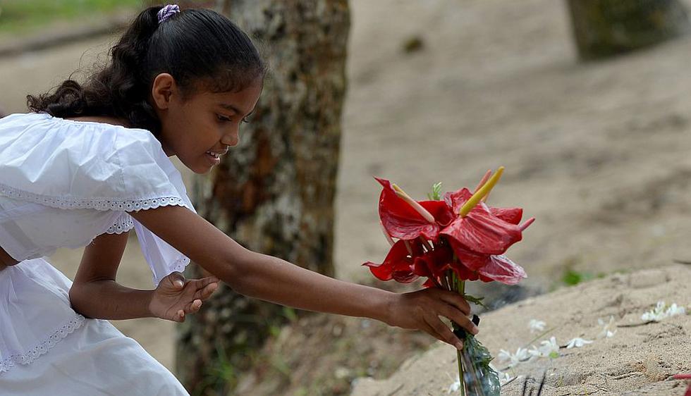 Niña deja ofrenda floral en el poblado costero de Peraliya, en Sri Lanka. Cerca de 40,000 personas murieron en dicho país. (AFP)