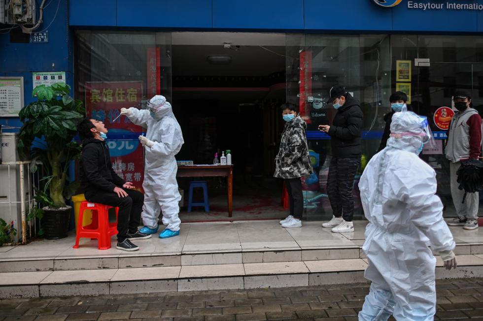 Las personas esperan en la fila mientras un trabajador médico toma una muestra con un hisopo de una persona para analizar si es portador del nuevo coronavirus en Wuhan, provincia central de Hubei, China. (Foto: AFP/Héctor Retamal)