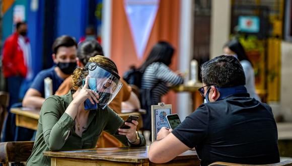 Un grupo de personas usa mascarillas y protectores faciales durante una prueba piloto de la apertura de un restaurante en la zona turística de Chorro de Quevedo, en Bogotá, el 1 de septiembre de 2020. (Foto de Juan BARRETO / AFP).