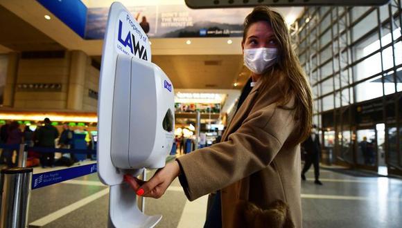 Una mujer que lleva una máscara protectora usa desinfectante de manos al llegar al Aeropuerto Internacional de Los Ángeles, Estados Unidos. (Foto: AFP/Frederic J. Brown)