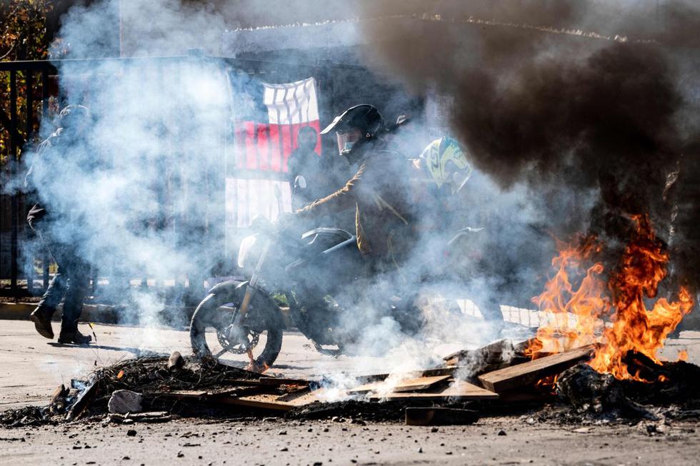 Un grupo de policías cruza sobre basura quemada que utilizaron manifestantes a modo de protesta por la falta de alimentos en Santiago de Chile. (AFP / MARTIN BERNETTI)