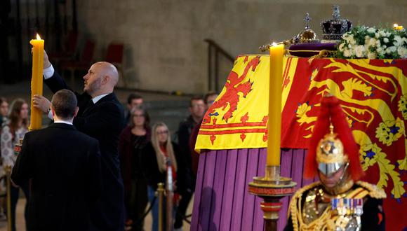 Se quita la cera de una vela junto al ataúd de la reina Isabel II, tumbada en el interior del Westminster Hall, en el Palacio de Westminster en Londres el 18 de septiembre de 2022. (Foto de Chip Somodevilla / POOL / AFP)