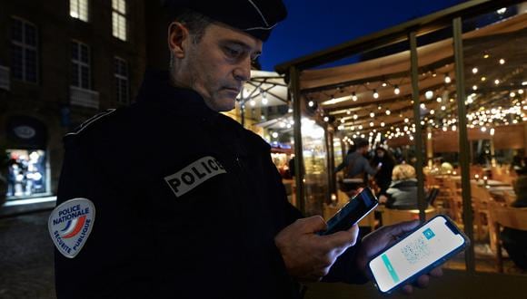 Un policía revisa el pase de salud de Covid-19 de un cliente en un bar en Saint-Malo, noroeste de Francia, el 19 de noviembre de 2021.  (Foto: JEAN-FRANCOIS MONIER / AFP)