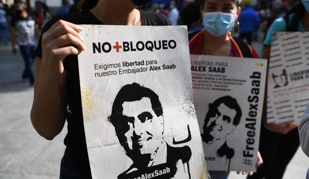 La gente sostiene carteles con la imagen del empresario colombiano Alex Saab, quien se encontraba distanciado a Estados Unidos, durante una manifestación para exigir su liberación. (Foto: Federico Parra / AFP)