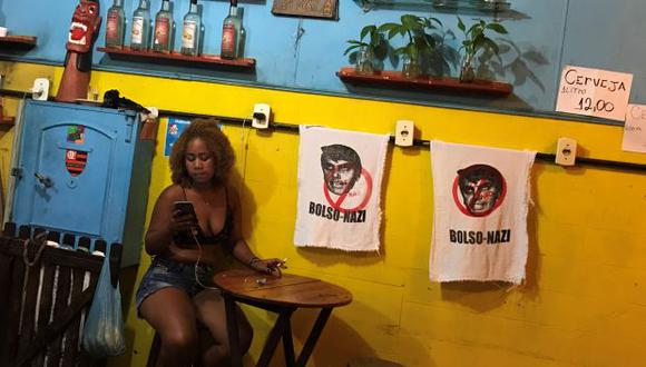Una mujer sentada junto a letreros con la imagen del candidato presidencial brasileño Jair Bolsonaro en un bar en Río de Janeiro. (Foto: Reuters)