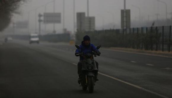 Un hombre chino monta su bicicleta eléctrica durante un día contaminado en Pekín, China. (Foto referencial: EFE)