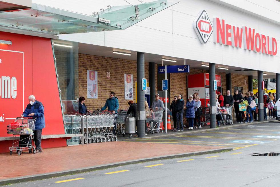Los compradores hacen cola frente a un supermercado en el suburbio de Devonport en Auckland (Nueva Zelanda). (AFP / DAVID ROWLAND).
