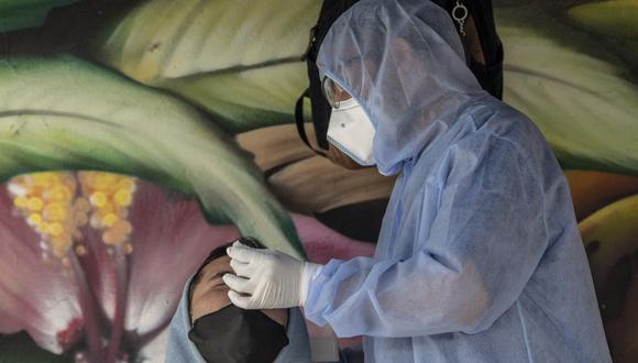 Foto referencial. Un trabajador de salud recolecta una muestra de hisopo para una prueba de coronavirus COVID-19 de un hombre en Bogotá el pasado 21 de diciembre de 2020. (Juan BARRETO / AFP)
