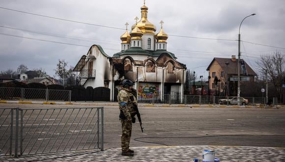 Un militar ucraniano hace guardia en una calle frente a una iglesia dañada en la ciudad de Irpin, al noroeste de Kiev, el 13 de marzo de 2022. (Foto: Dimitar DILKOFF / AFP)