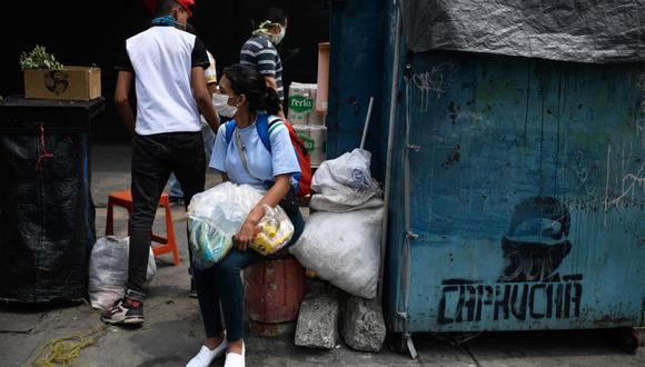 Una mujer usa una máscara facial como medida preventiva contra el nuevo coronavirus, mientras compra en un mercado en el barrio de Petare, Caracas, Venezuela. (Foto: AFP/Federico Parra)