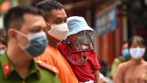 Un grupo de residentes esperan ser examinados en un improvisado centro de pruebas rápidas en Hanoi, mientras Vietnam registra un aumento en los casos del coronavirus. (NGUYEN / AFP)