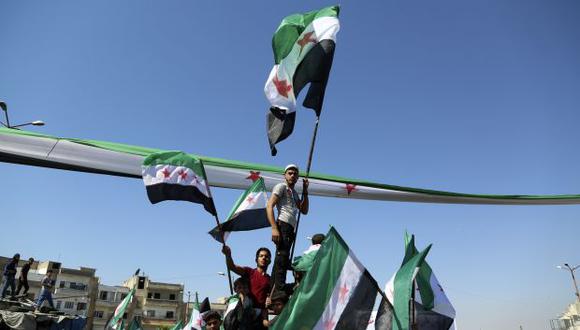 Un hombre sirio ondea una bandera de la oposición, durante una manifestación contra el gobierno y pidiendo la liberación de los detenidos en sus prisiones. (Foto: AFP)