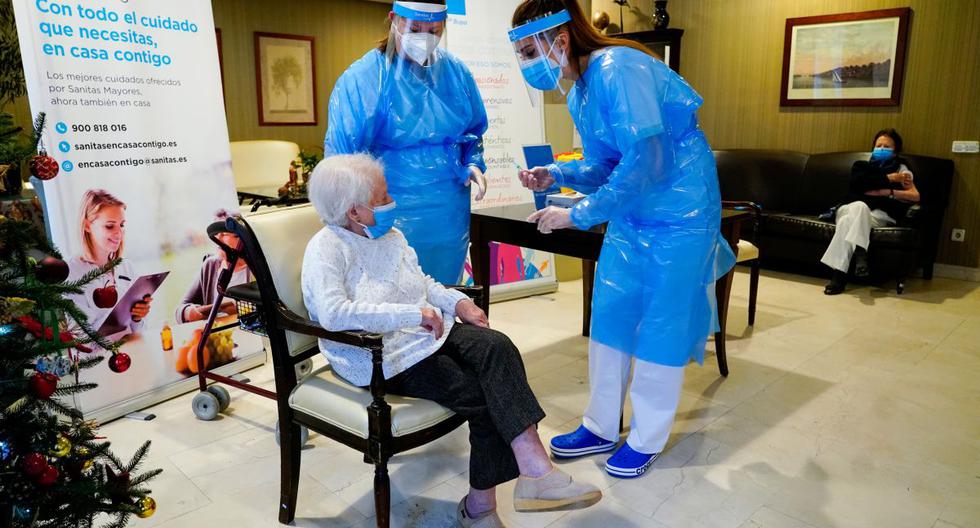 Una empleada del asilo de ancianos "El Viso" habla con Amalia González, de 96 años, antes de que le inyecten una dosis de la vacuna Pfizer-BioNTech COVID-19 en Madrid, España, el 7 de enero de 2021. (REUTERS/Juan Medina).
