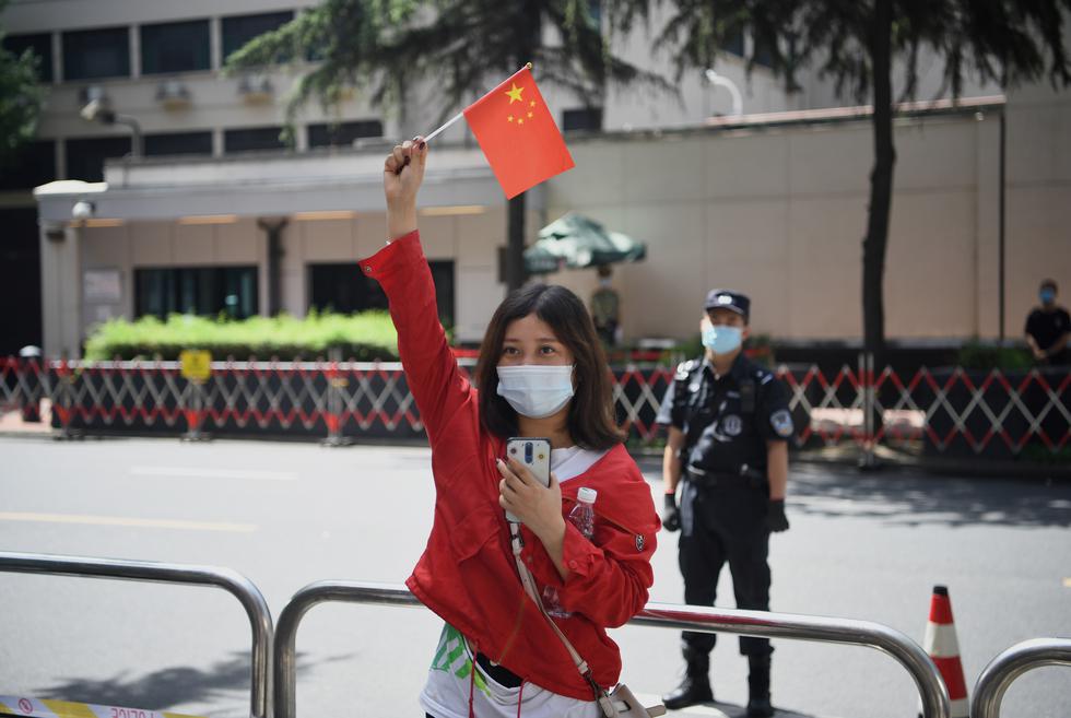 Una mujer ondea una bandera china frente al consulado de Estados Unidos en Chengdu. (Foto: Noel Celis / AFP)