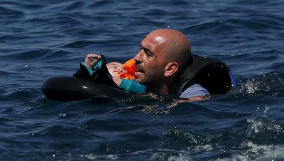 Otro naufragio. Refugiado sirio transporta a un bebé a la orilla. (Reuters)