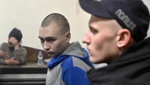 El soldado ruso Vadim Shishimarin (centro) observa desde el palco del acusado la apertura de su juicio por el cargo de crímenes de guerra por haber matado a un civil, mientras su viuda Kateryna Shelipova (izquierda) reacciona en el tribunal de distrito de Solomyansky en Kiev el 18 de mayo. , 2022. (Foto de Genya SAVILOV / AFP)