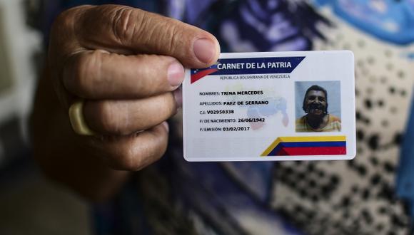 La venezolana Trina Páez muestra su "Carnet de la Patria", un documento de identidad electrónico destinado a organizar y regular los beneficios sociales del gobierno. (Foto: AFP)