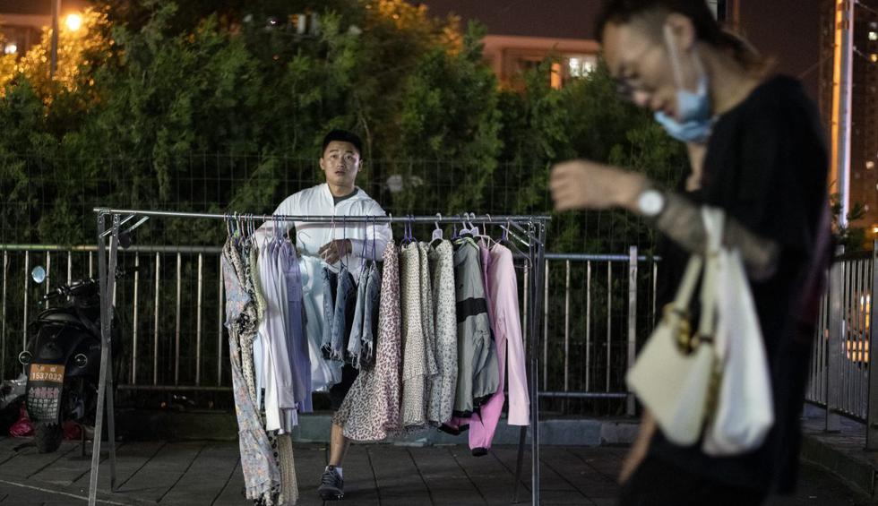 Un ciudadano que vende ropa espera a los clientes a lo largo de una calle en Beijing. China, el primer país golpeado por el nuevo coronavirus, se recupera progresivamente de la epidemia que ha hundido su economía. (NOEL CELIS / AFP).
