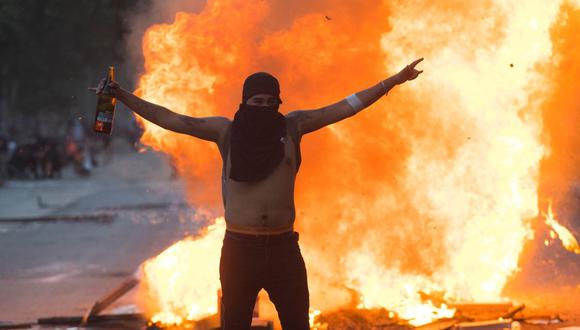 Un hombre vitorea junto a una barricada en llamas durante una nueva jornada de manifestaciones en la Plaza Italia. (Foto: EFE)