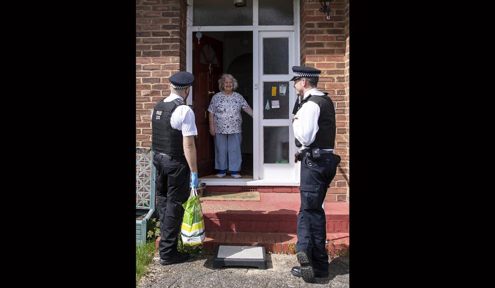 Los oficiales de policía APS Simon Hardwick (izquierda) y PS Liam Hack hablan con Gwendalyn Iles, de 94 años, en su casa en una visita especial como parte de la Operación Nogi en Croydon, sur de Londres. (Foto: AFP/JUSTIN TALLIS)