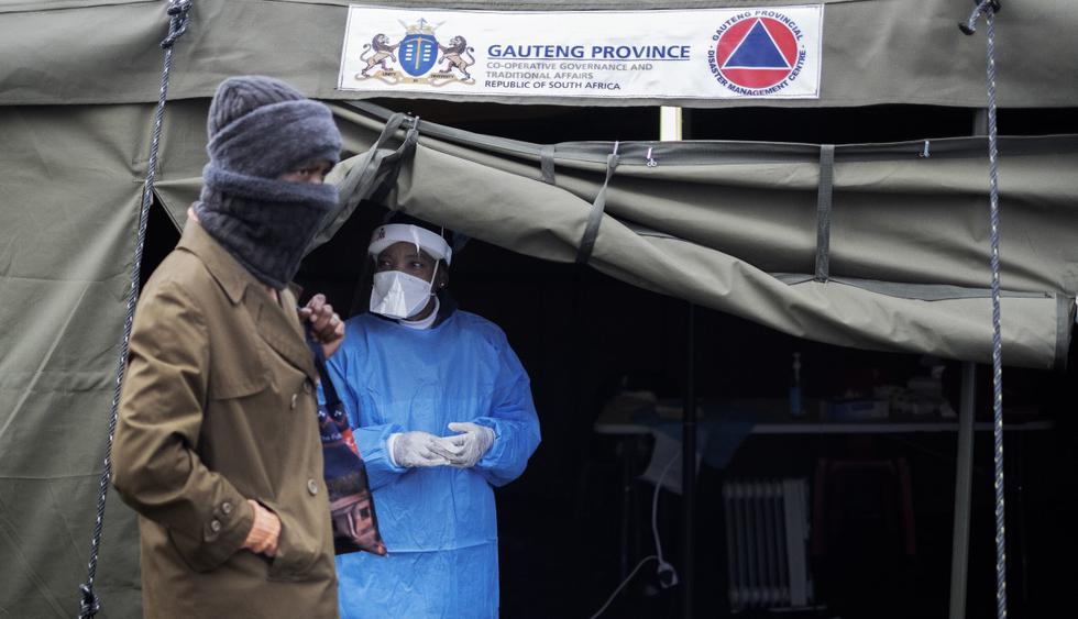 Un trabajador de la salud observa como un residente de Johannesburgo espera en línea para hacerse una prueba de coronavirus en la Clínica Sophia Town el 28 de abril de 2020. (Luca Sola / AFP).