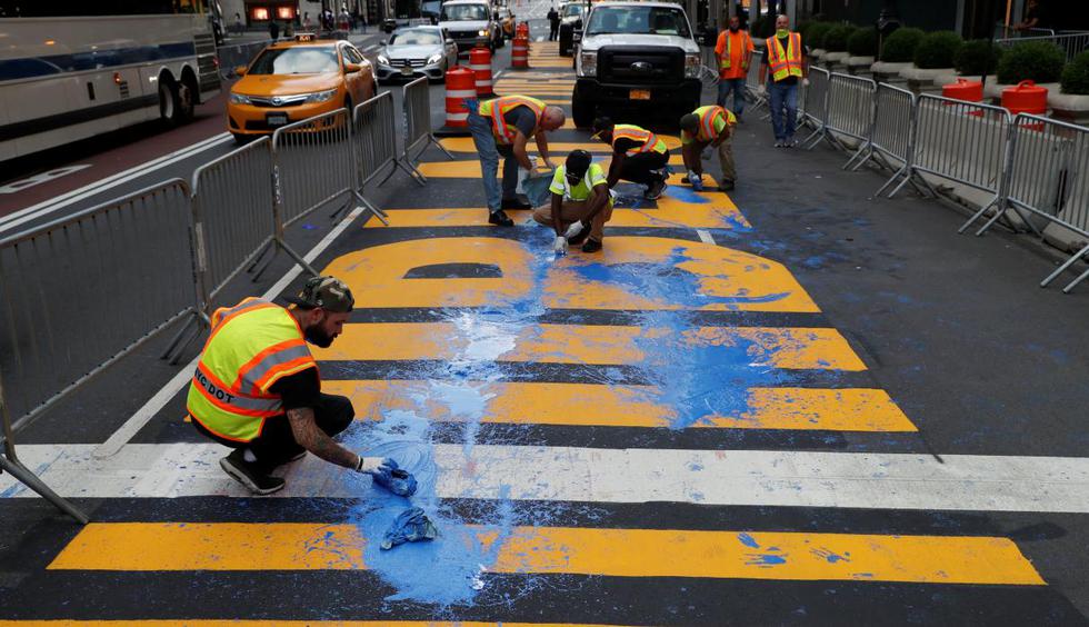 Un video de vigilancia mostró a tres personas derramando pintura azul el viernes alrededor de las 4 de la tarde sobre las letras enormes pintadas sobre la Quinta Avenida en Manhattan. Trabajadores son vistos limpiando en Nueva York. (REUTERS/Andrew Kelly).