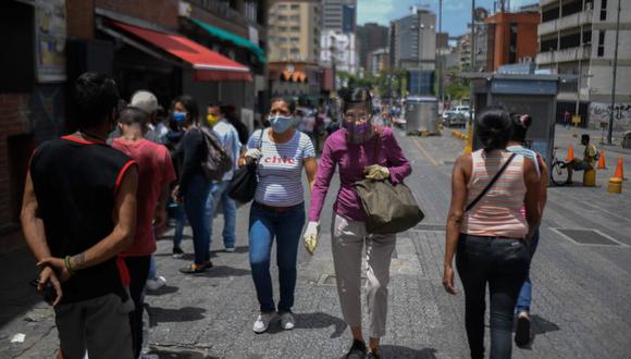 Las personas que usan gafas nasales caminan por el bulevar Sabana Grande luego de que el gobierno intensificara un bloqueo nacional como medida preventiva contra la propagación del coronavirus. (AFP/Federico PARRA).