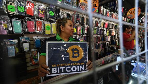 Una vendedora sostiene un cartel que dice "Bitcoin aceptado" en una tienda en San Salvador, el 26 de enero de 2022. (Foto: MARVIN RECINOS / AFP)