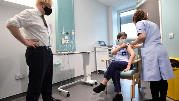 El primer ministro británico, Boris Johnson (izquierda), observa cómo una mujer, de nombre Susan Cole, recibe una dosis de la vacuna AstraZeneca en el Chase Farm Hospital, en el norte de Londres. (Stefan Rousseau / POOL / AFP)