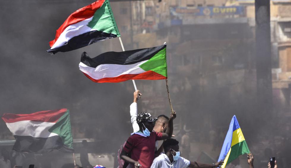 Manifestantes sudaneses izan banderas nacionales. (Foto de AFP)