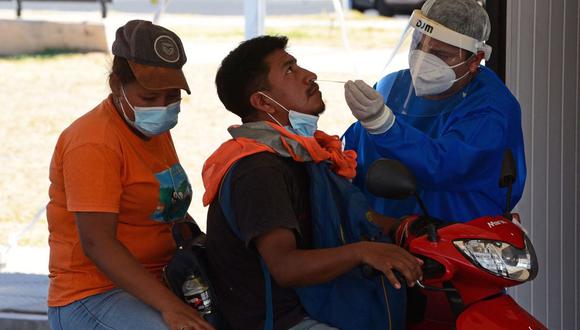 Un trabajador de la salud toma muestras de la enfermedad del nuevo coronavirus COVID-19 en un hombre en un centro de pruebas en Asunción, el 24 de enero de 2022. (Foto de NORBERTO DUARTE / AFP)