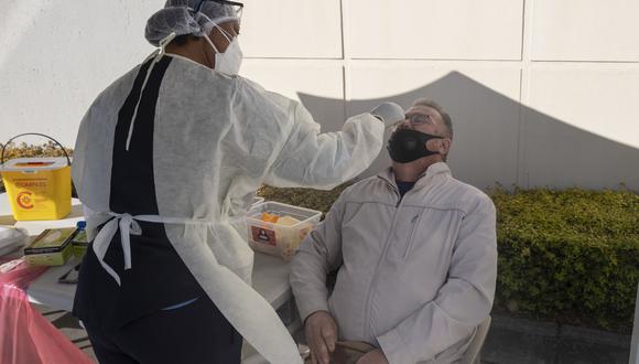 Un hombre recibe un hisopo nasal, de un trabajador de la salud que usa equipo de protección personal (EPP), para ser examinado por COVID-19 en el Fourways Life Hospital en Johannesburgo el 28 de junio de 2021. (Foto: Emmanuel Croset / AFP)